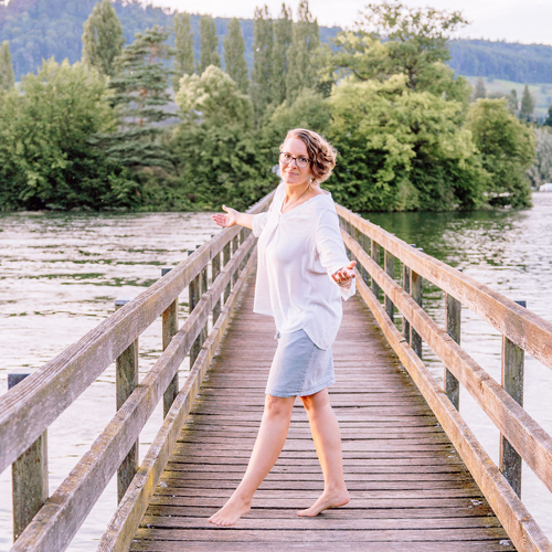 Corinna Fanni, Coach für Nervensystemregulation und emotionale Balance tänzelt auf der Brücke der Insel Werd auf dem Bodensee.